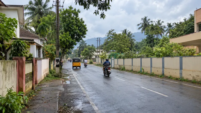 Tropical residential road in Asaripallam with an auto-rickshaw, motorcycles, homes and coconut palms