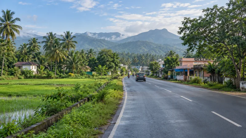 Road through Boothapandi with homes, green fields, coconut palms and Western Ghats foothills