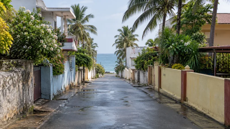 Quiet coastal residential lane in Kanyakumari with tropical homes and a view towards the sea