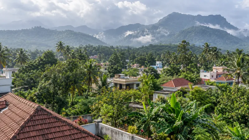 Green foothill settlement in Kulasekharam with homes, tropical gardens and the Western Ghats