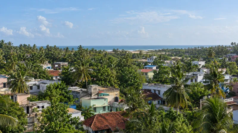 Coastal Manavalakurichi settlement with homes, coconut trees and the Arabian Sea horizon